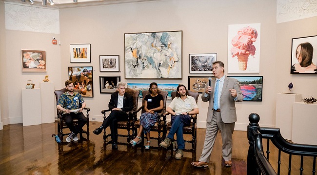 man speaking besides others seated