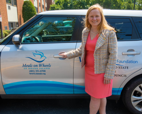 woman posng in front of meals on wheels vehicle