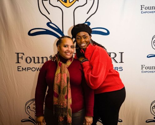 two women posing for a picture in front of fountainhead backdrop