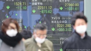 people wearing masks with asian stock prices in background